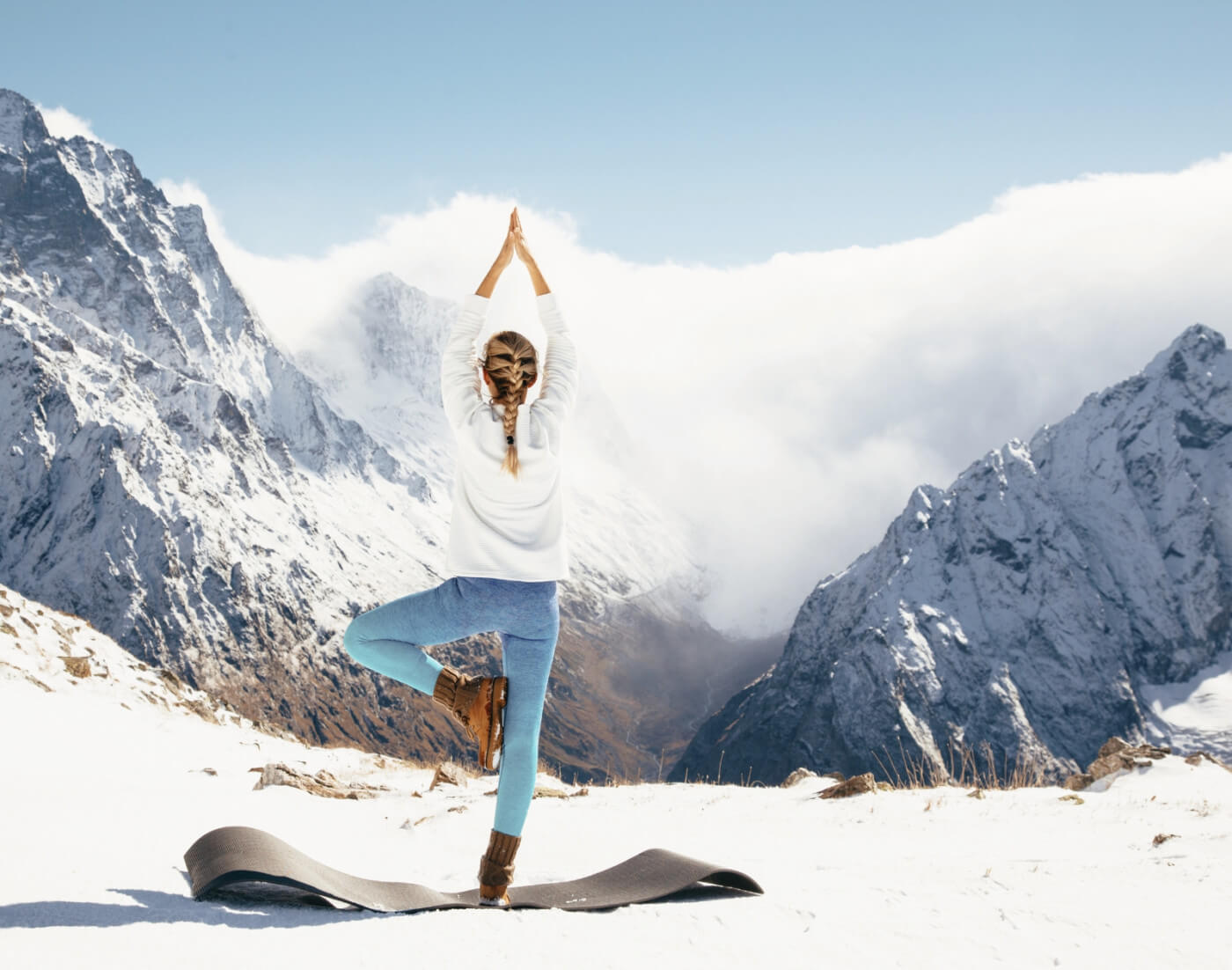 Woman doing yoga on a snowy mountain | vitamin supplement benefits during winter article