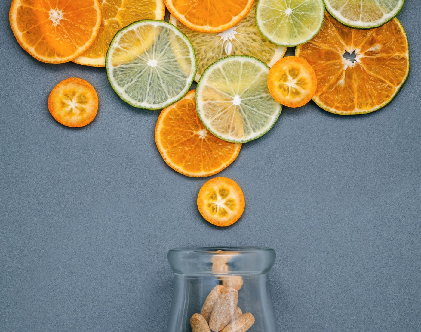 Citrus fruits above a bottle of vitamins | Vitamin Supplements in cold weather article 