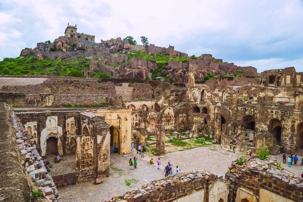 A panoramic shot capturing the sprawling fort with its massive granite walls and bastions. The surrounding greenery and the urban juxtaposition of Hyderabad in the distance can be a captivating contrast.