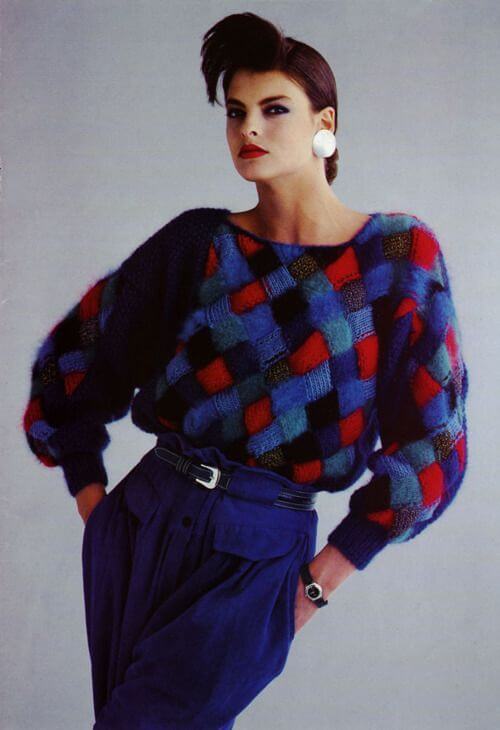 The model wears an ‘80s style sweater and large silver disc earrings.