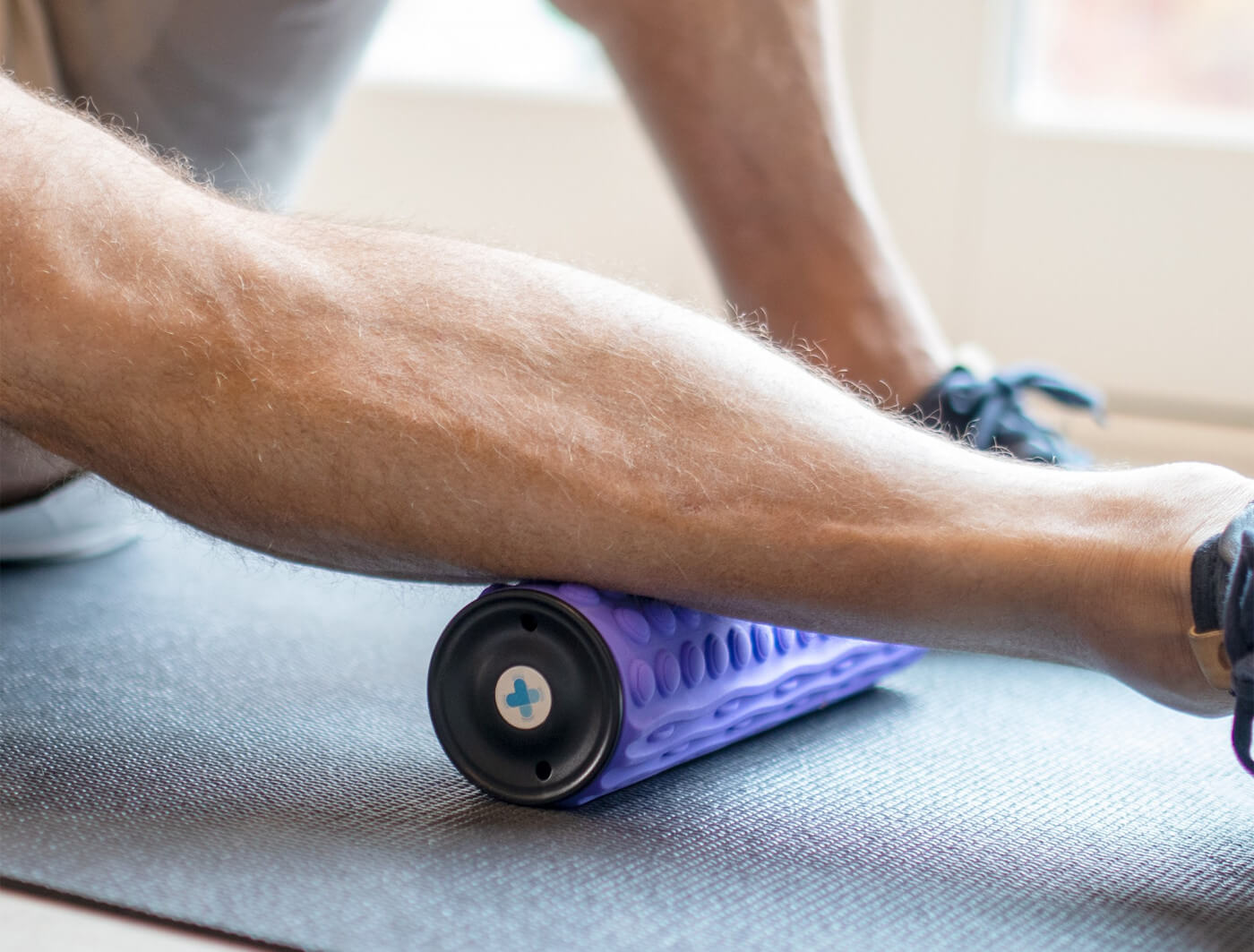 Person resting calf muscles on foam roller.