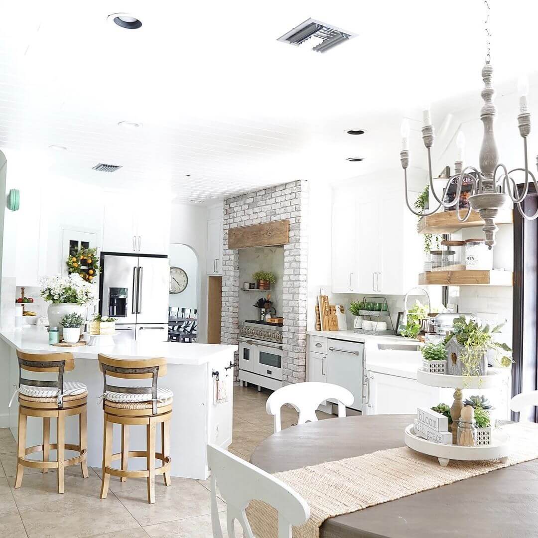 Farmhouse kitchen design with an irregular shaped kitchen island all white with brick and silver accents and stainless steel appliances 