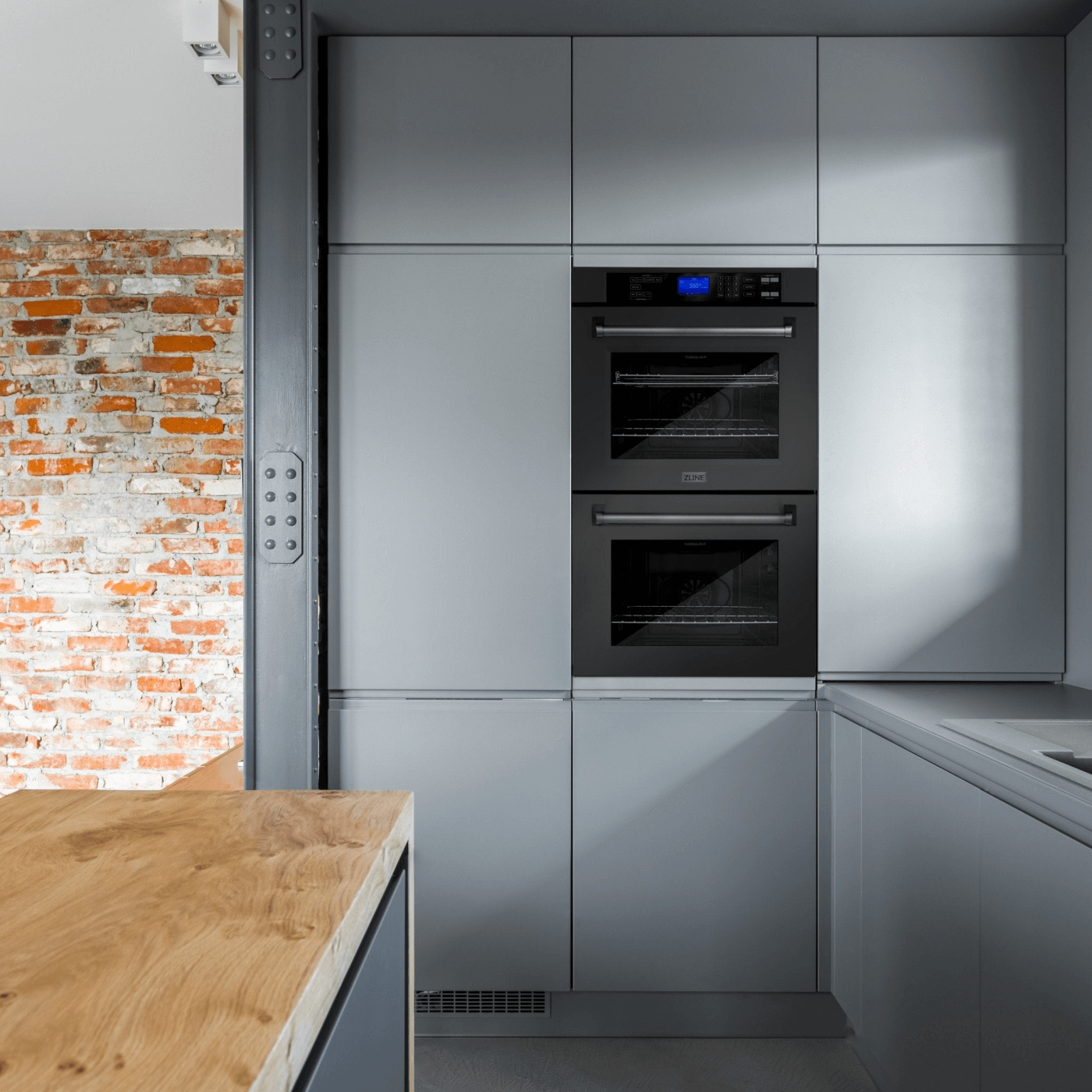 ZLINE 30 in. Double Wall Ovens in Black Stainless Steel mounted on a wall with blue cabinetry surrounding.