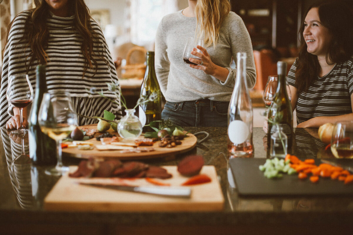 women gathering around a table with wine and food on cutting boards