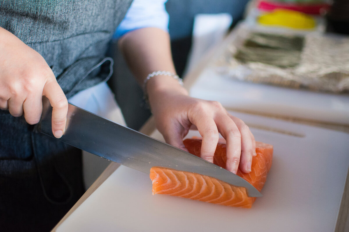 knife slicing salmon on cutting board