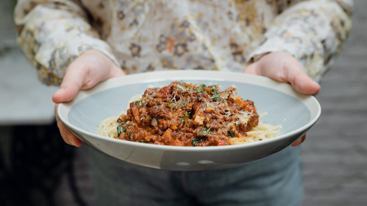 woman holding bowl with meat sauce