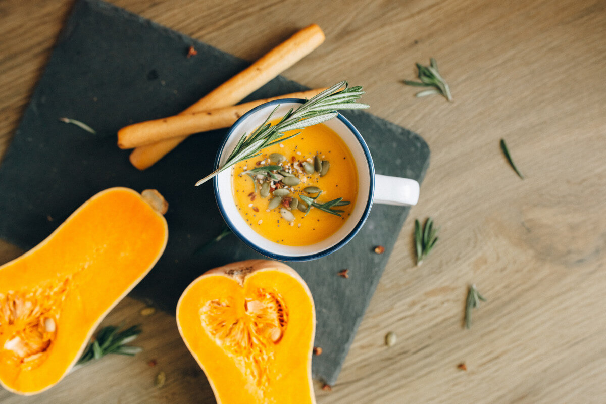 cut butternut squash and soup with rosemary on a cutting board