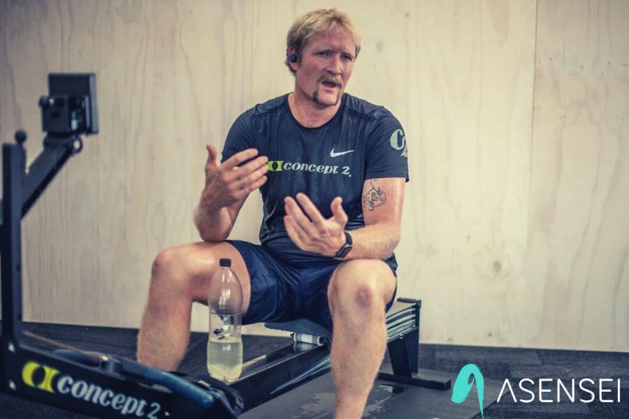 Eric Murray sits on a rowing machine, explaining a beginner rowing workout
