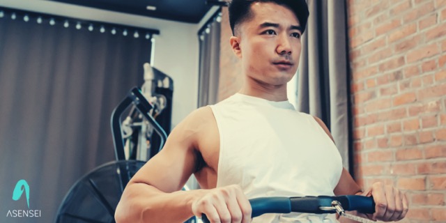 Close-up shot of a man using an indoor rowing machine.