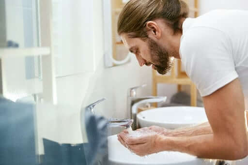 Man washing beard butter off his face