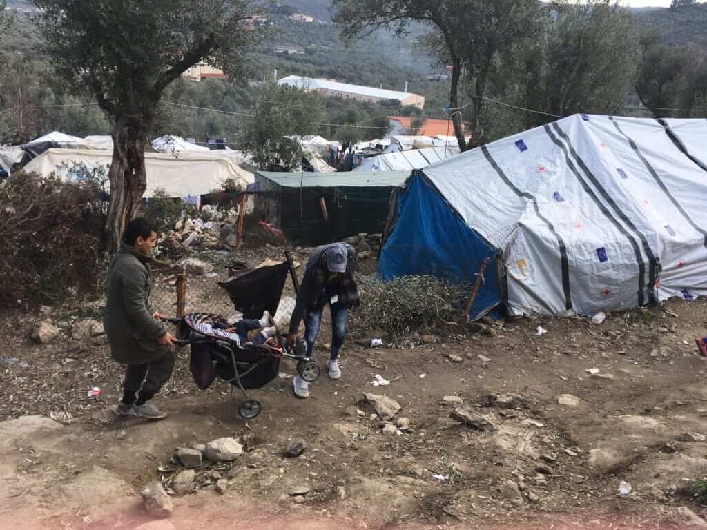 A father struggling to carry his child in a pushchair down the steep hillsides of the olive grove. A passerby came to his aid.