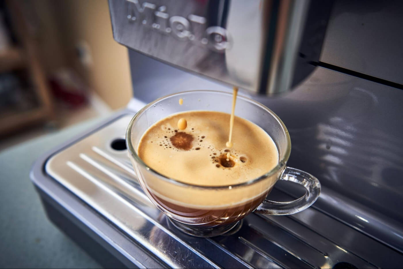 Espresso pouring into glass cup on a coffee machine