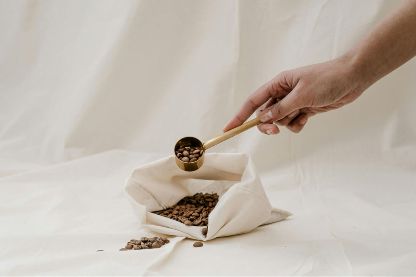 Hand scoops out coffee beans from an open coffee bag