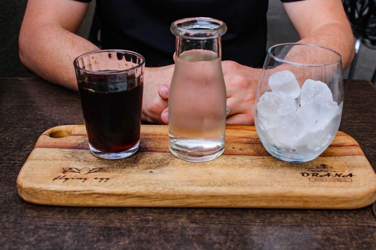Cold brew coffee concentrate, water, and ice on a wooden tray