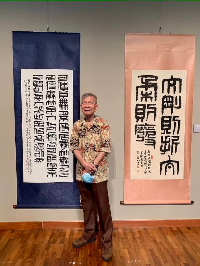 Singapore artist Wee Beng Chong with two of his Calligraphy scrolls at his art exhibition.