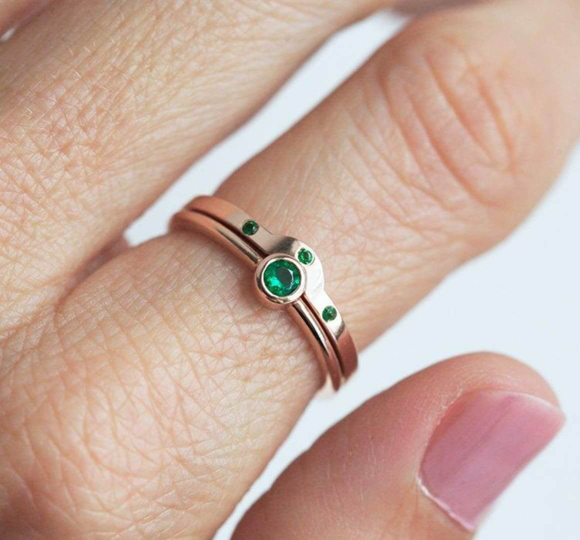 An emerald solitaire ring with matching emerald studded band by Capucinne.