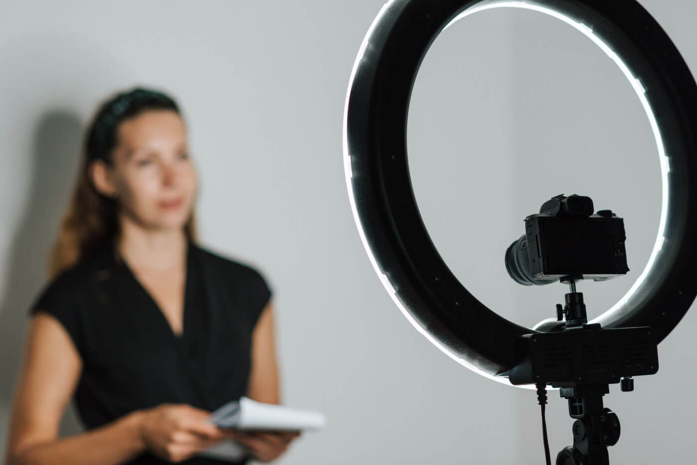 A woman recording a video of herself with a camera and ring light.