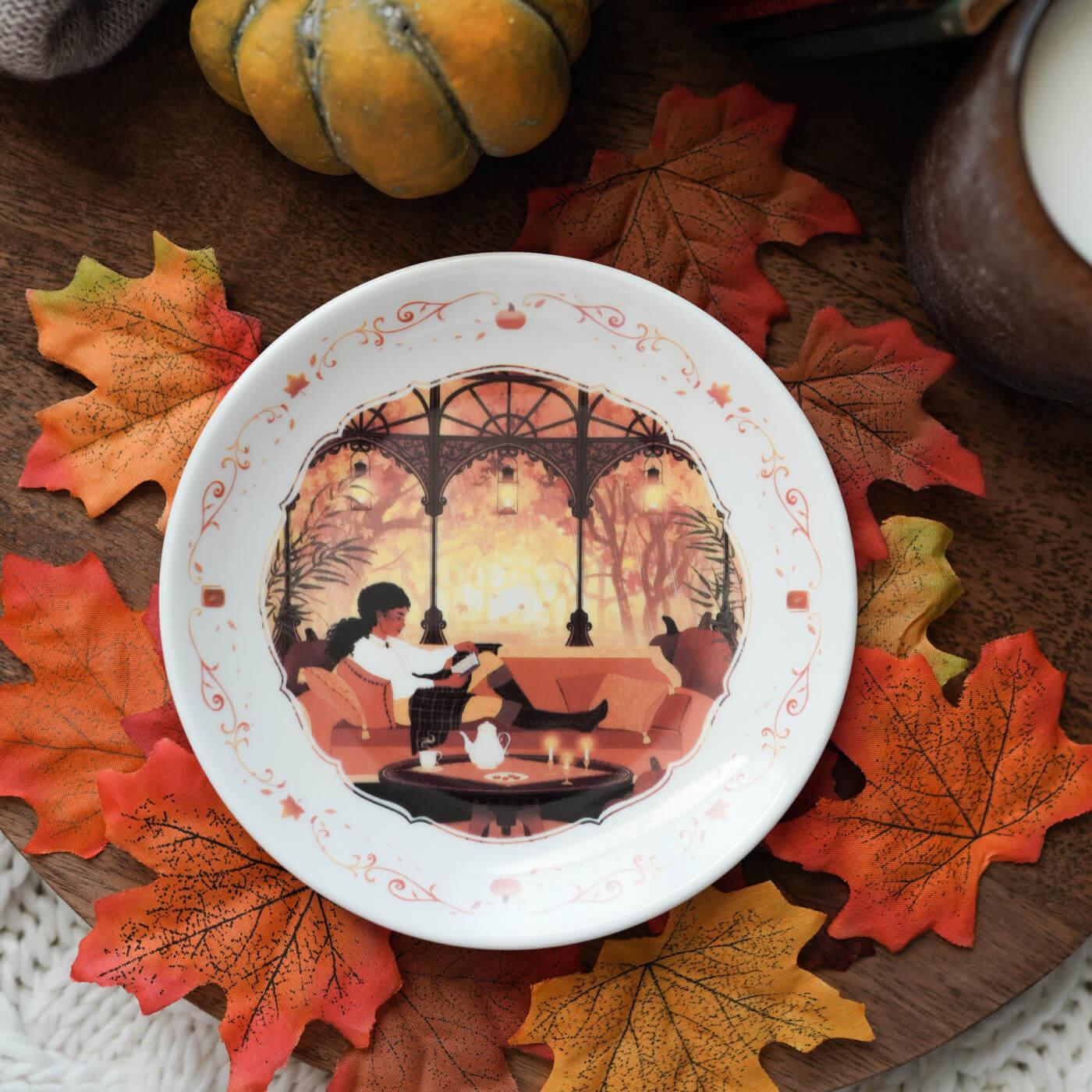 A decorative plate with a person reading in an autumn decorated book room with a window looking out into autumn