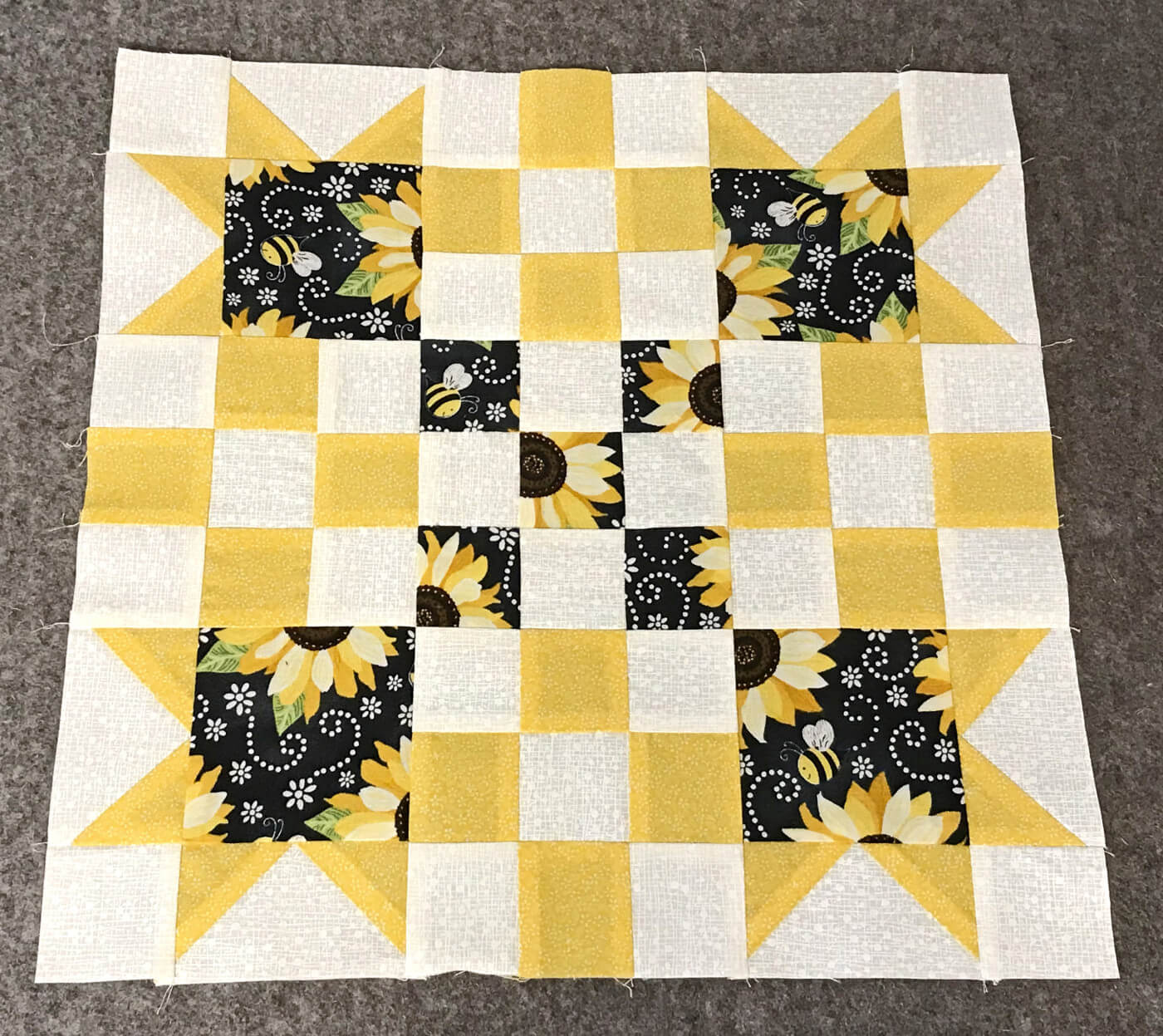 quilt block with yellow black and white 9 patch blocks and flying geese blocks in the corners