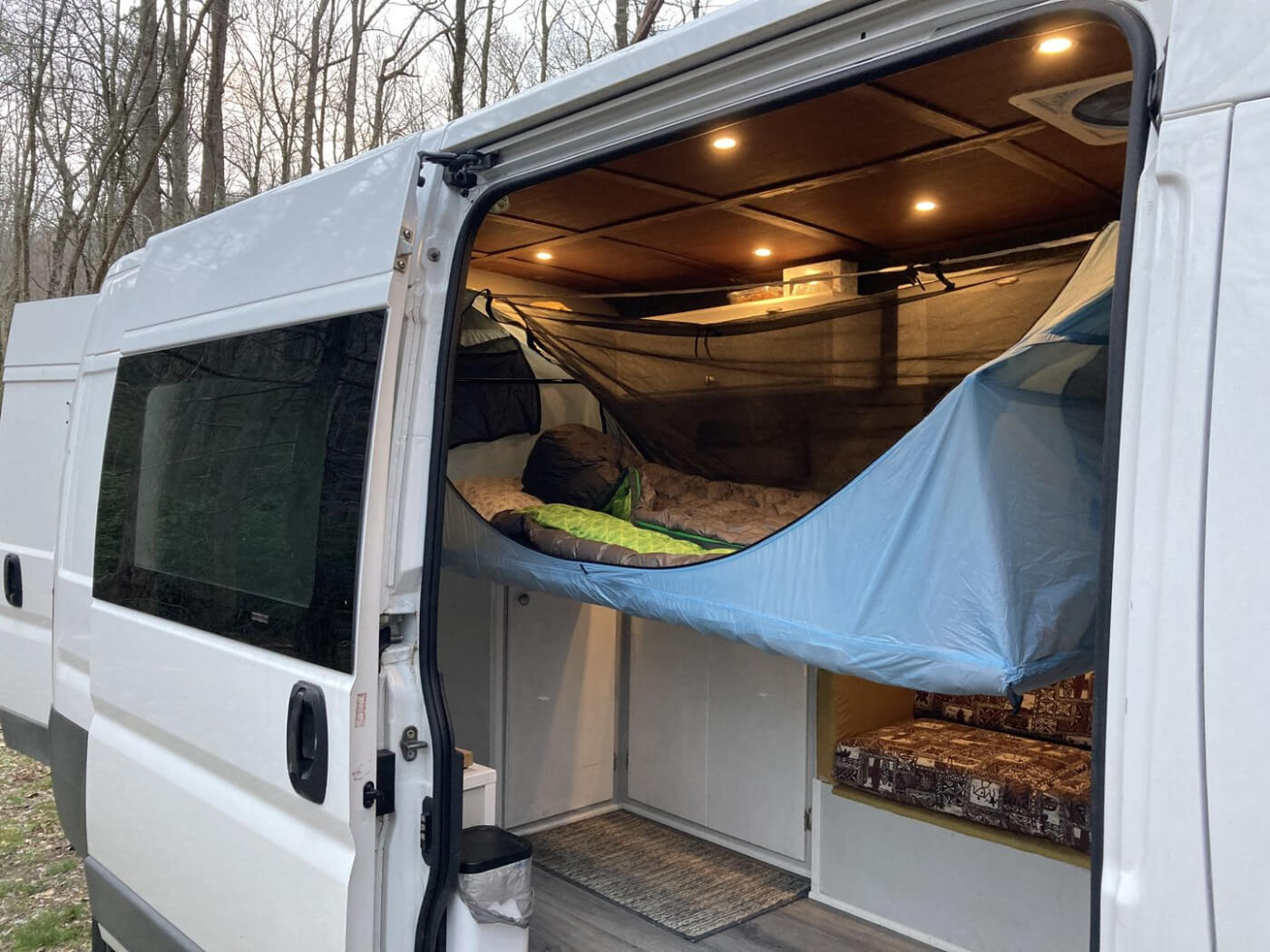 A haven tent hammock hanging from inside a van