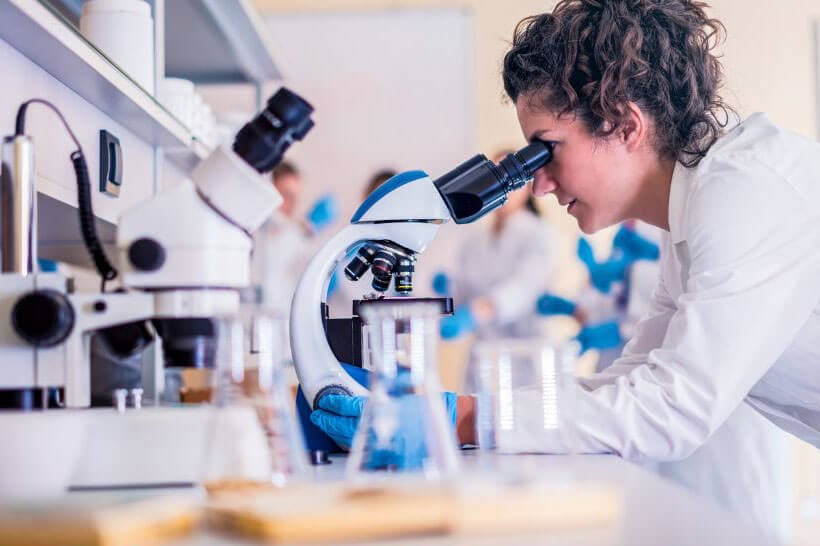 female scientist examines microscope for highest paying science jobs article